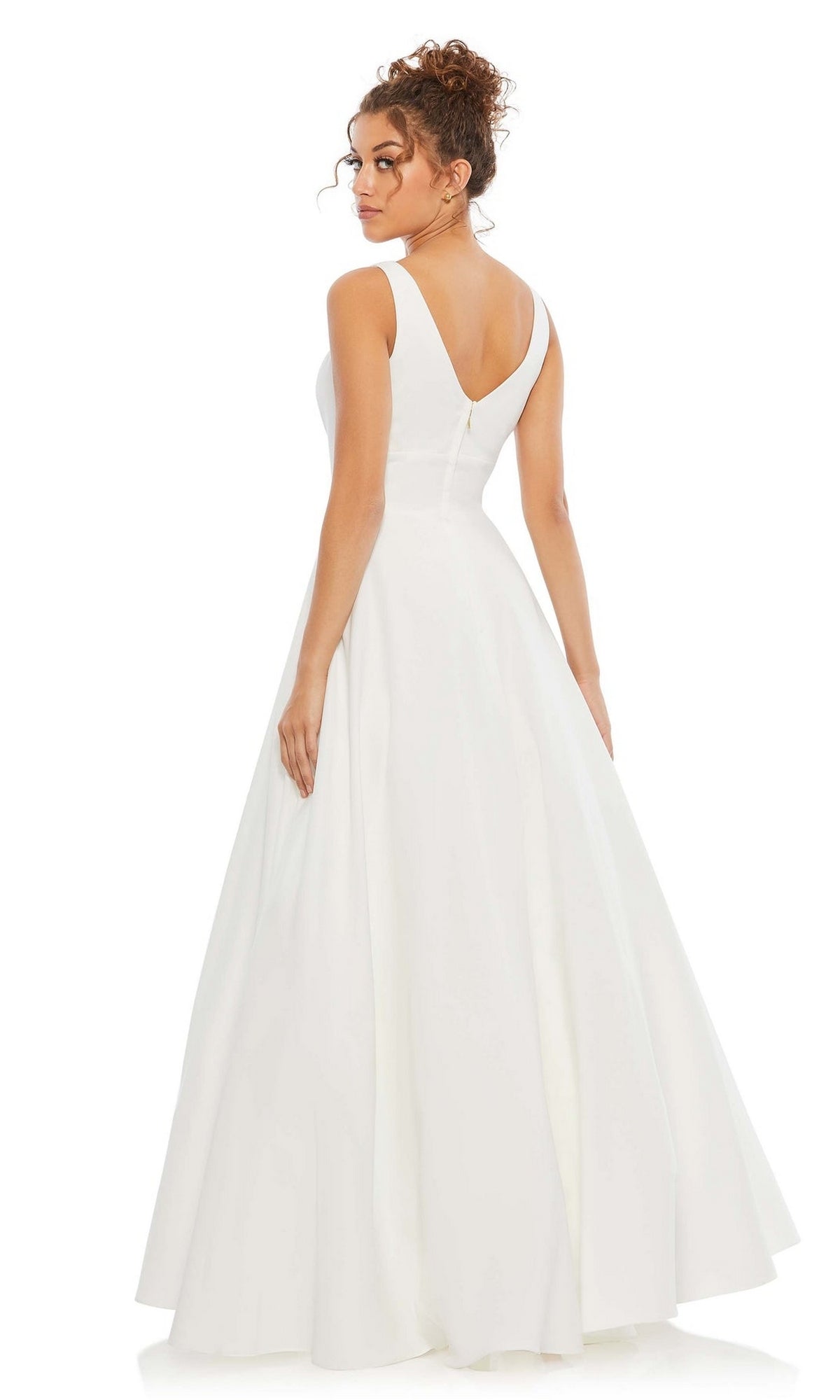 A woman in the Classic Long Prom Ball Gown: Mac Duggal 48924, a sleeveless, floor-length dress with a V-shaped back and full skirt, stands gracefully and looks over her shoulder.